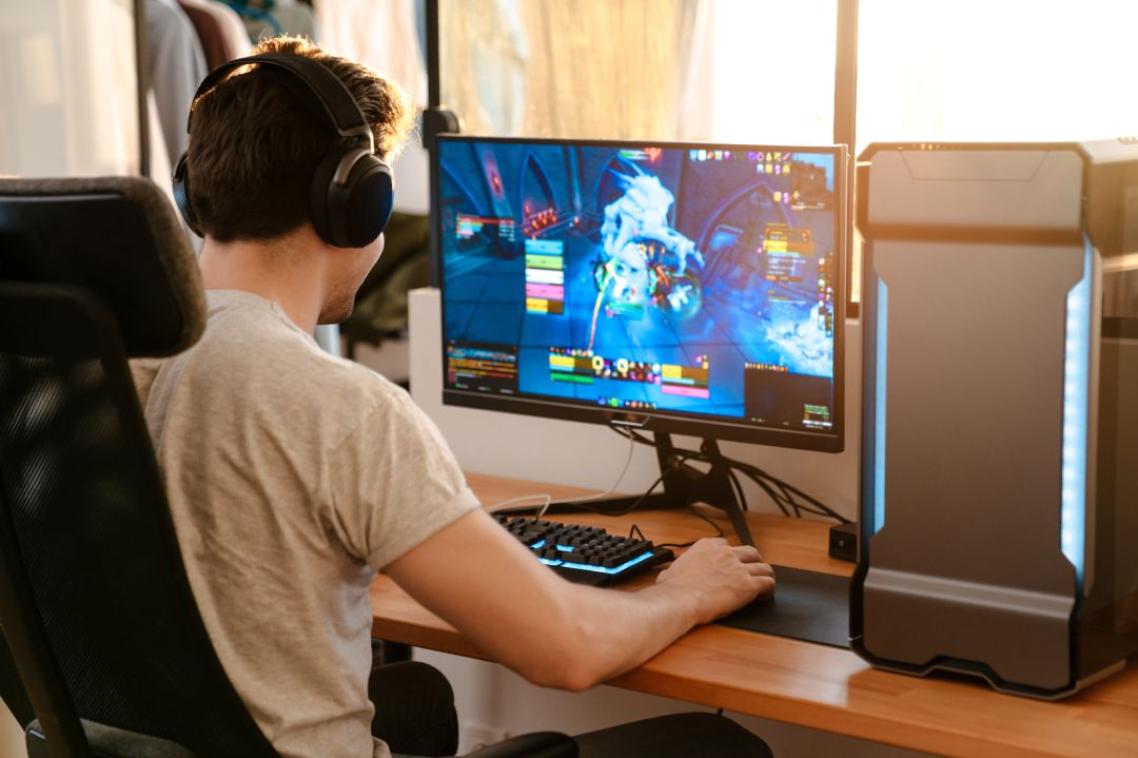 A young man sitting at his computer playing a video game. 