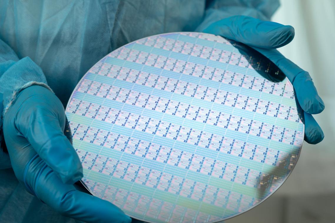 Gloved hands hold a large silicon disc.