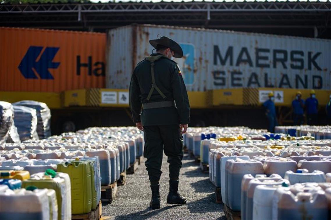 A man in a cowboy hat walking amongst a row of seized drugs