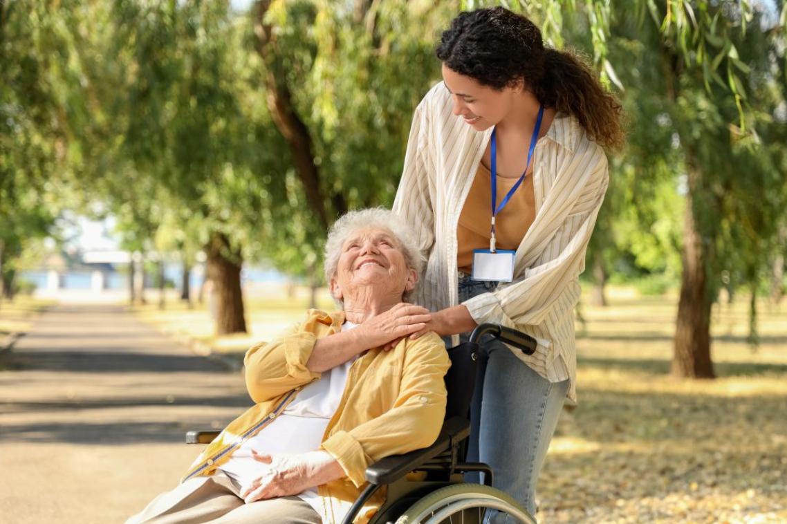 A woman in a wheel chair looking up towards her carer