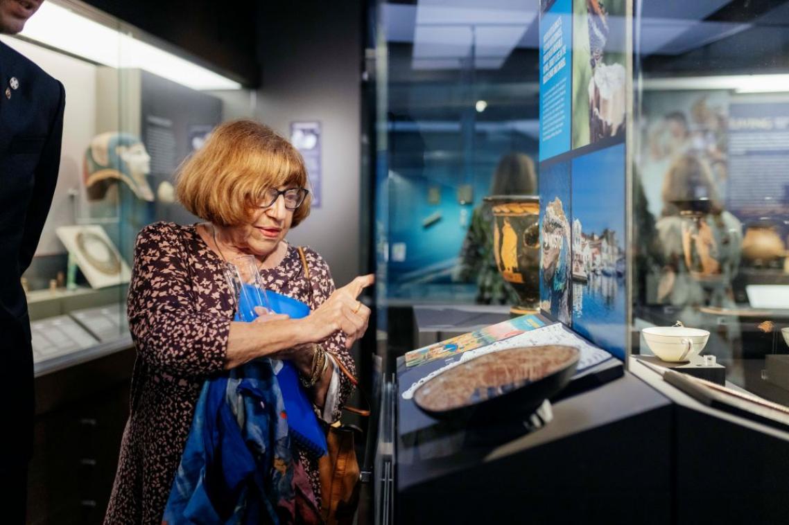A woman pointing enthusiastically at a glass cabinet
