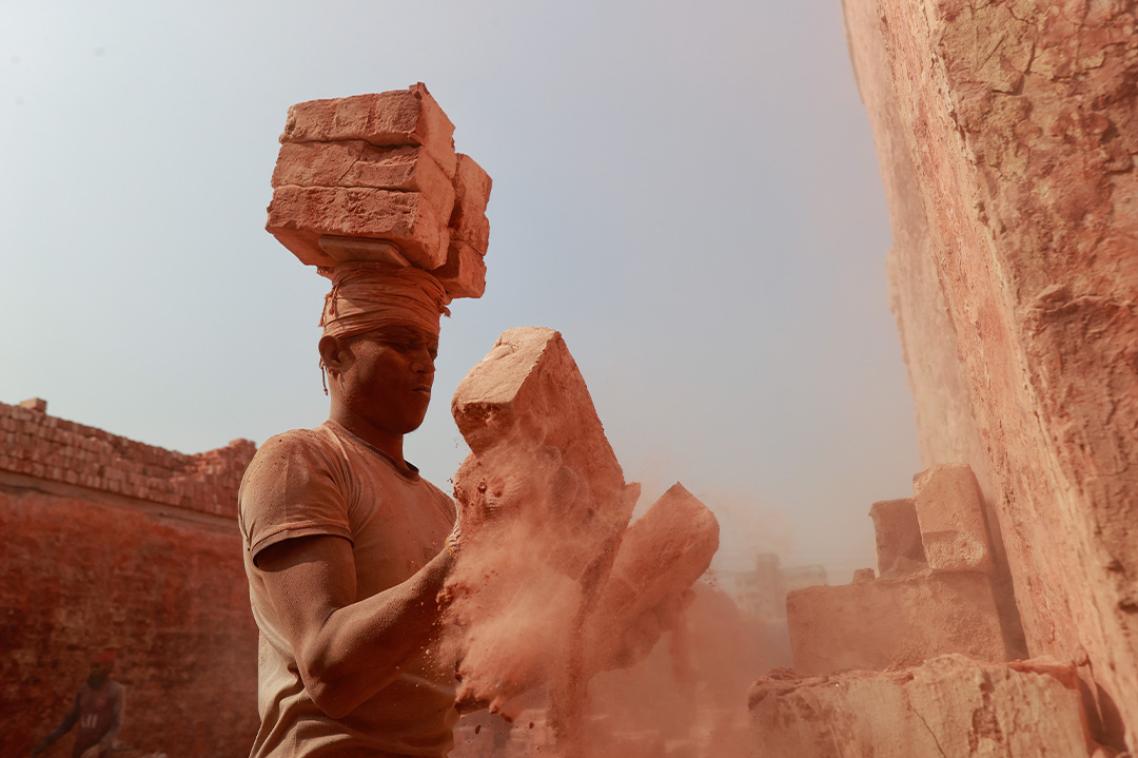 A man carries clay bricks. 