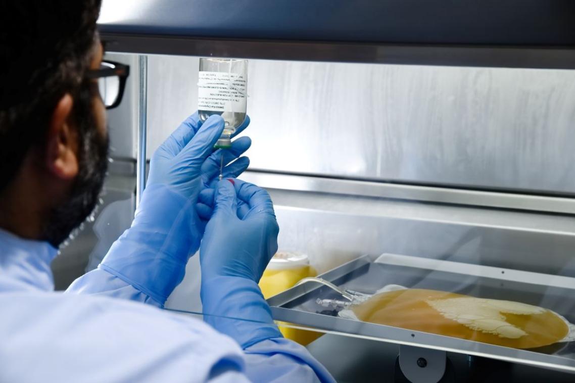 Scientist holding vial of clear liquid with bag of platelets nearby.