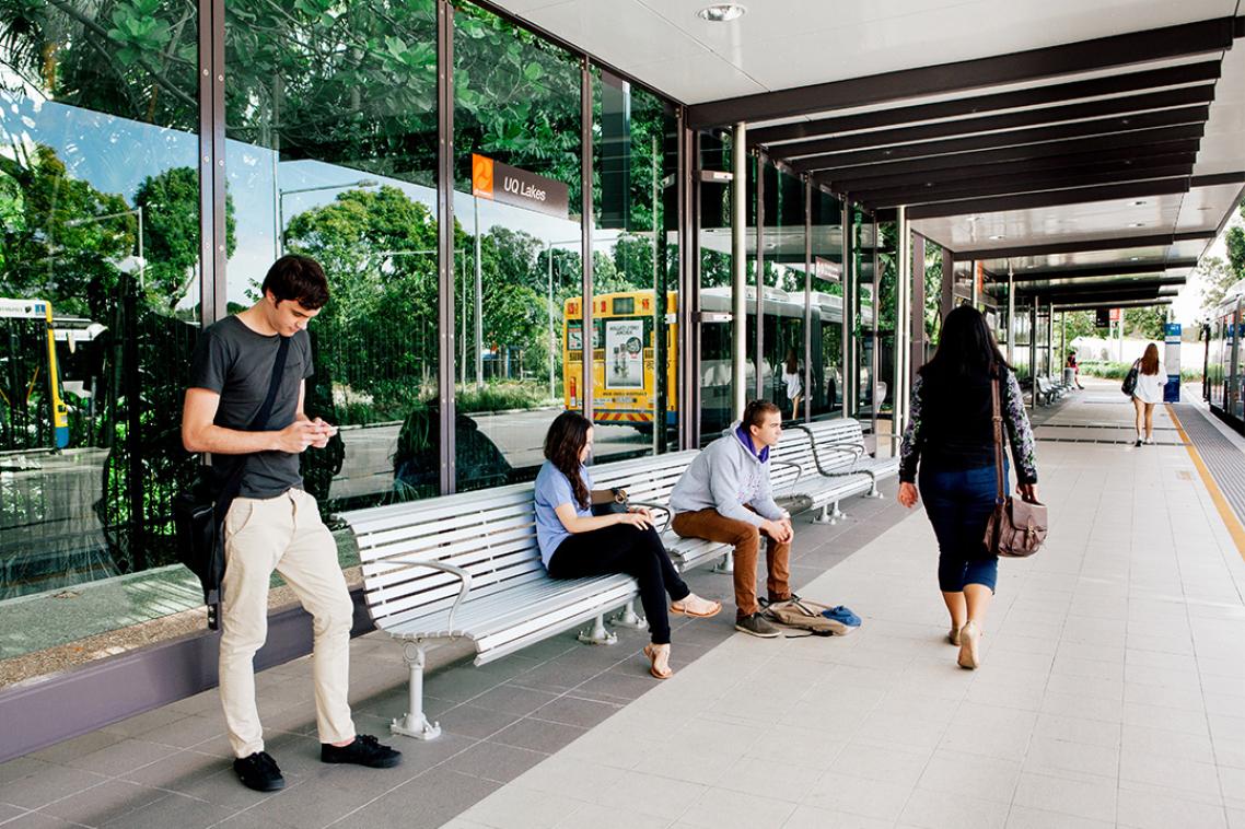 people sit on a bench at a bus stop 
