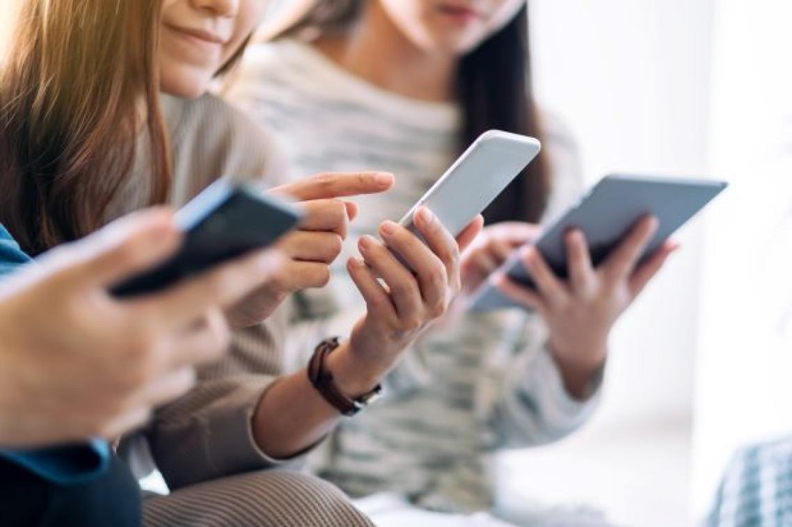 A group shot of three teenage girls looking down at mobile devices in their hands