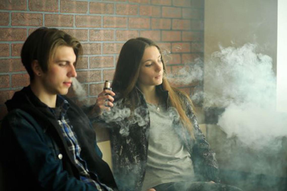 Two young people smoking e-cigarettes. Adobe