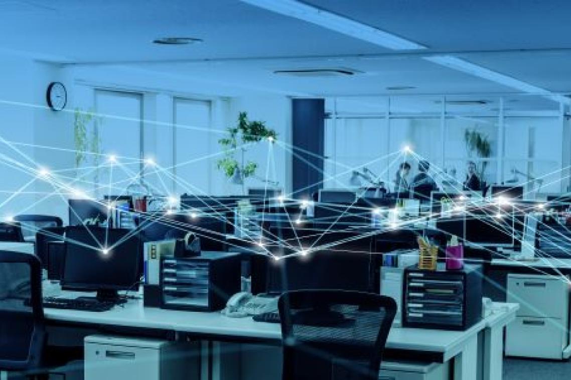 An office space with desks, chairs and monitors but no people, and a graphic of connecting lines linking each workstation.