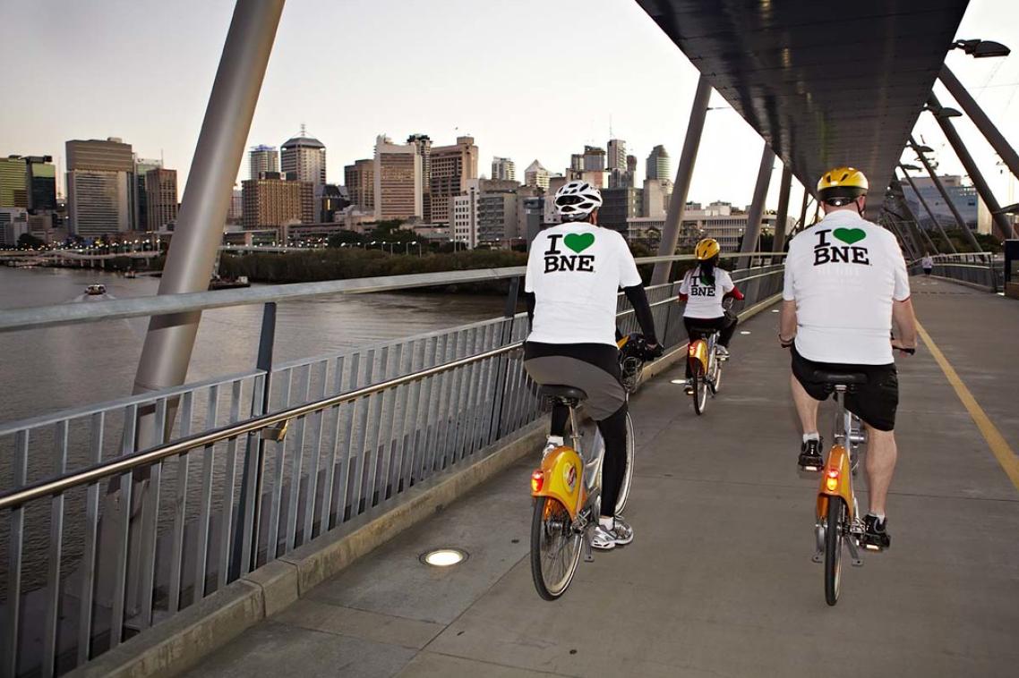 Two men on bicycles riding over a bridge on the Brisbane River