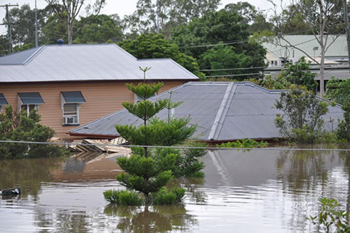 Floods inundating several homes with only the roof tiles visible of the one in the centre of the picture