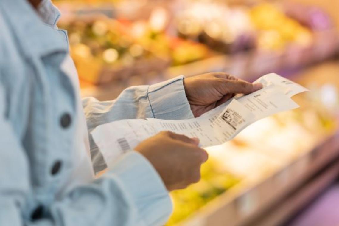 Woman looking at receipts in supermarket. Image, Adobe