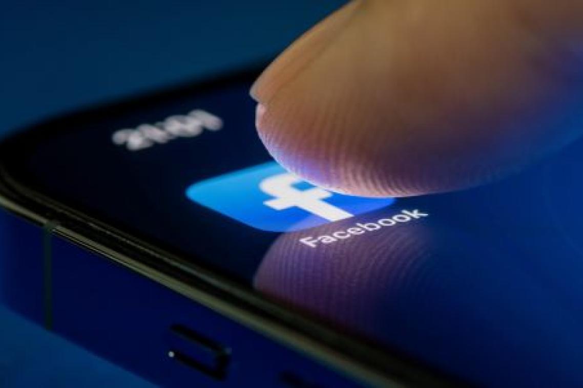 A fingertip pushes on the Facebook App on a mobile phone screen.