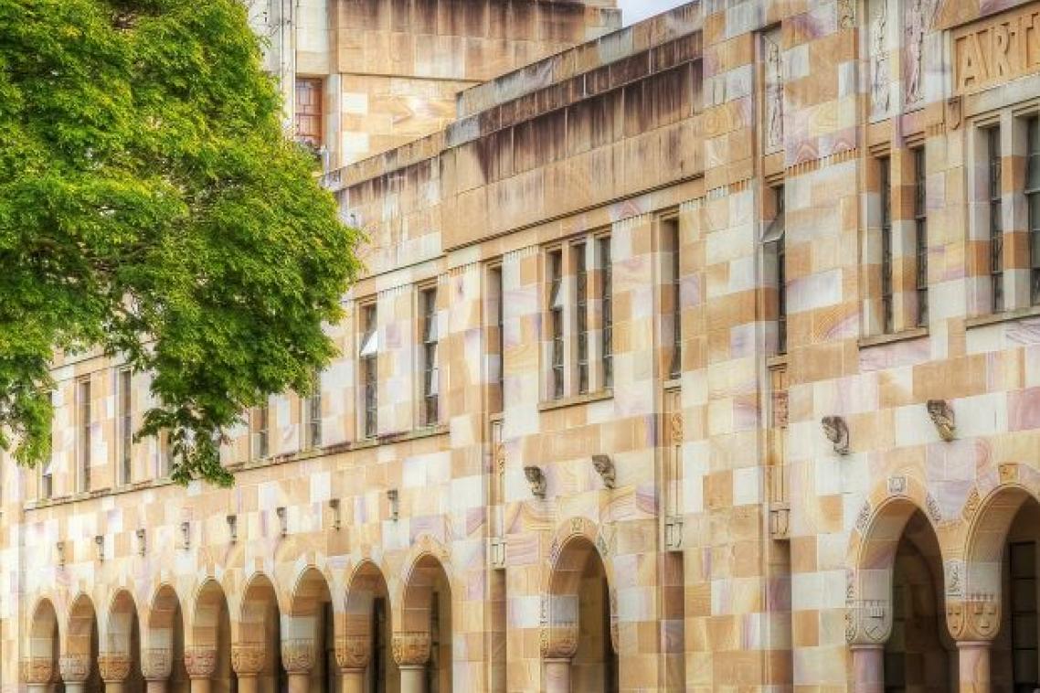 The sandstone buildings of UQ's Great Court with people wandering in the background.