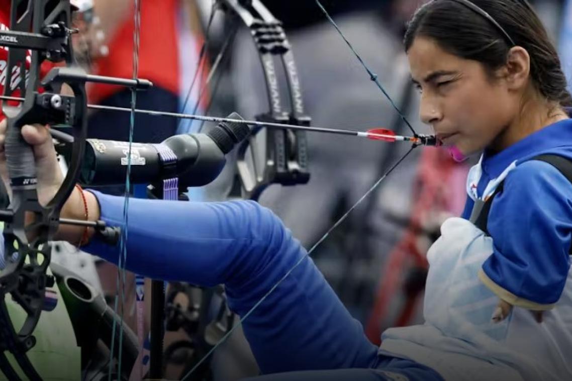 a woman sits in a chair and draws a bow with her foot and mouth