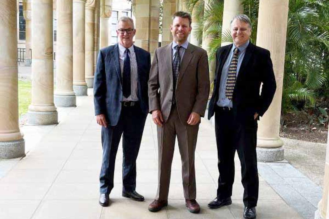Three men in suits standing in UQ's Great Court.