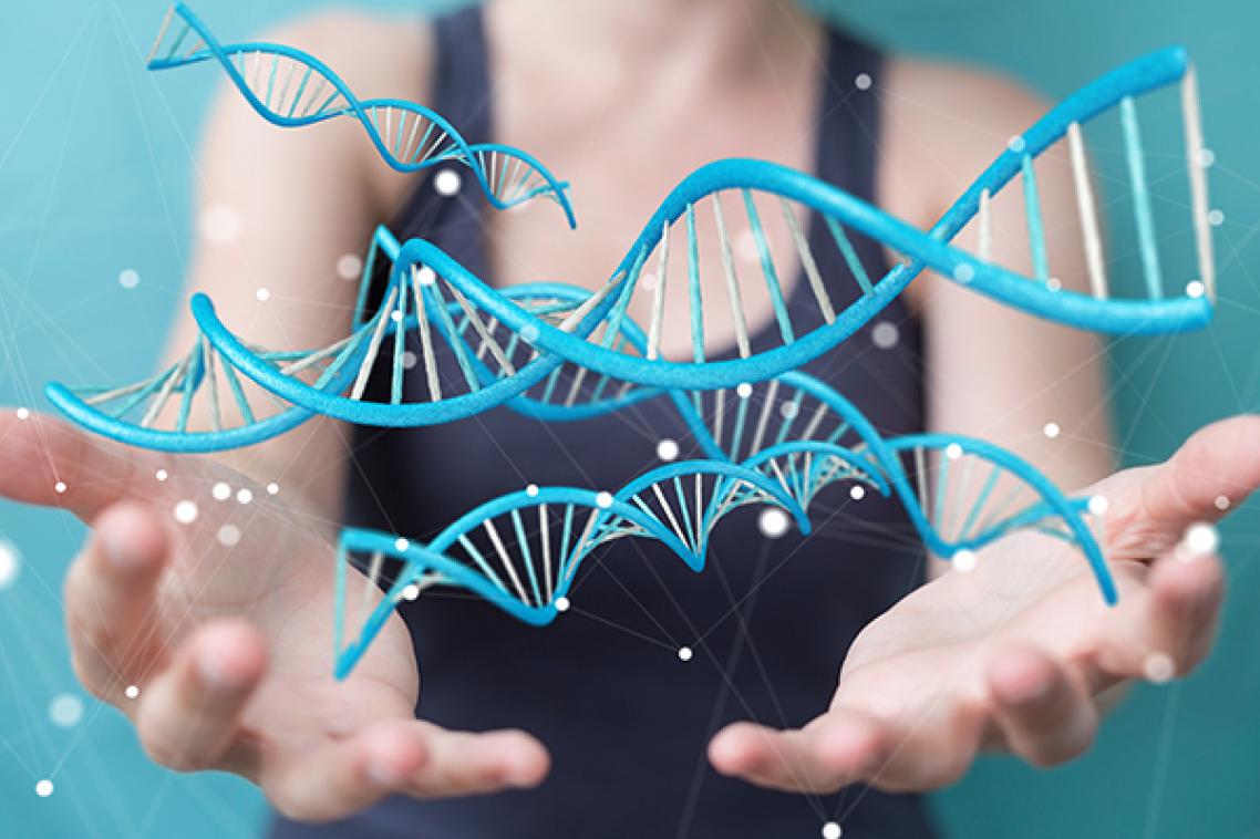 A woman stands in front of a blue background with graphic depiction of DNA