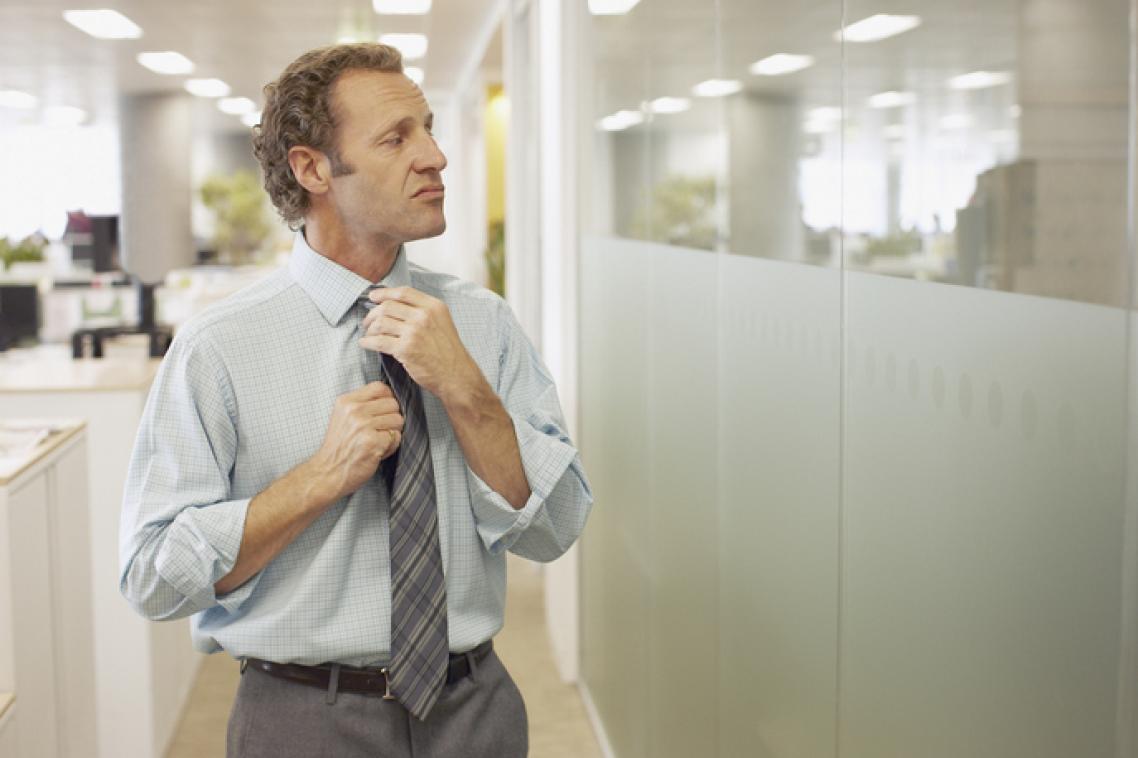 Businessman fixing his tie whilst looking at his reflection in a window