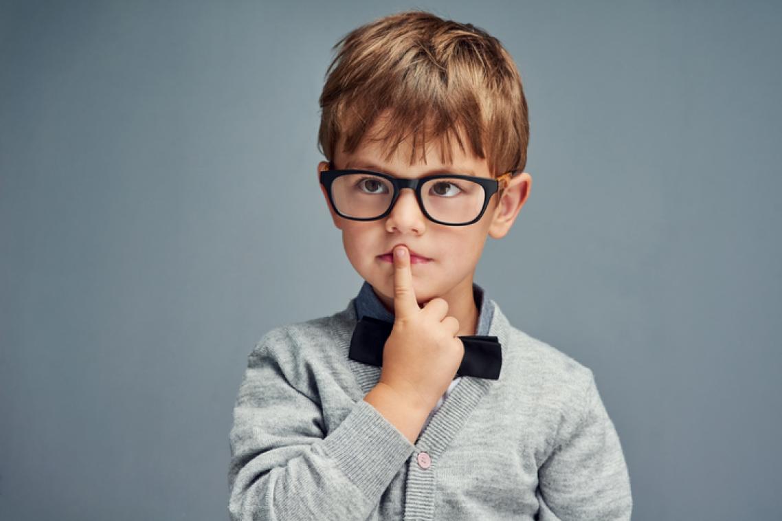 Pensive young boy with his index finger over his mouth