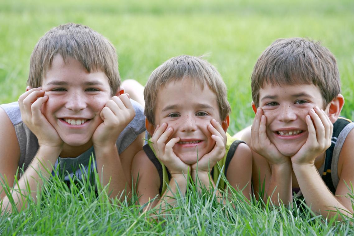 Stock image of three brothers lying next to each other in long grass