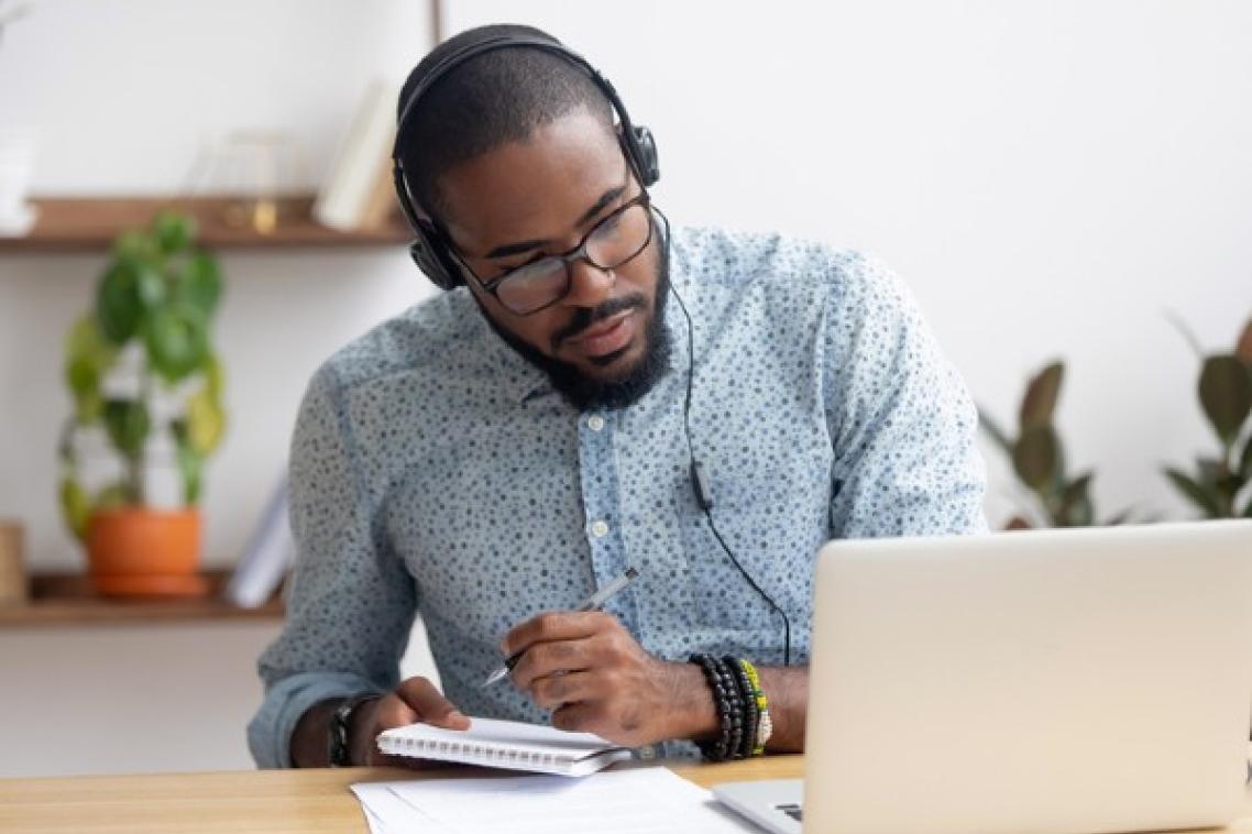 Man studying at desk with headphones on.
