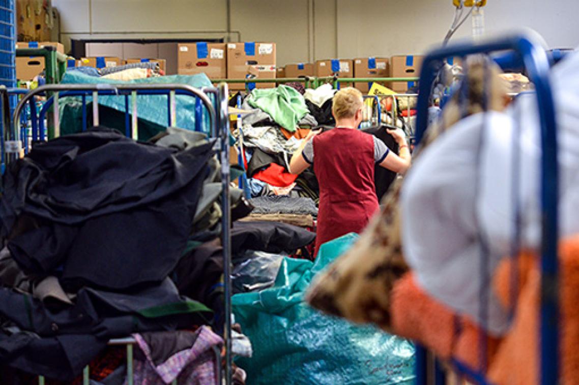 A woman sorting through piles of clothes at a charity shop