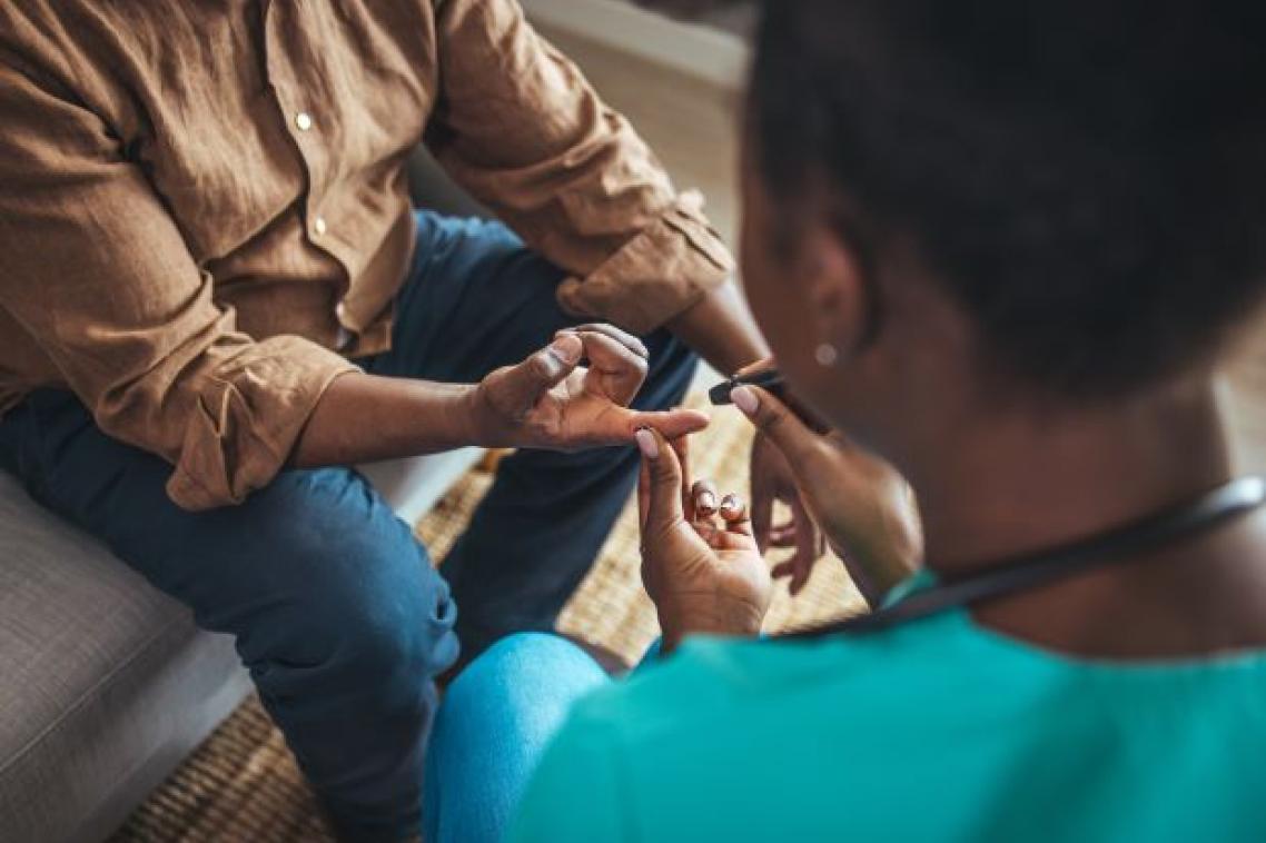 Woman taking blood sugar level of patient