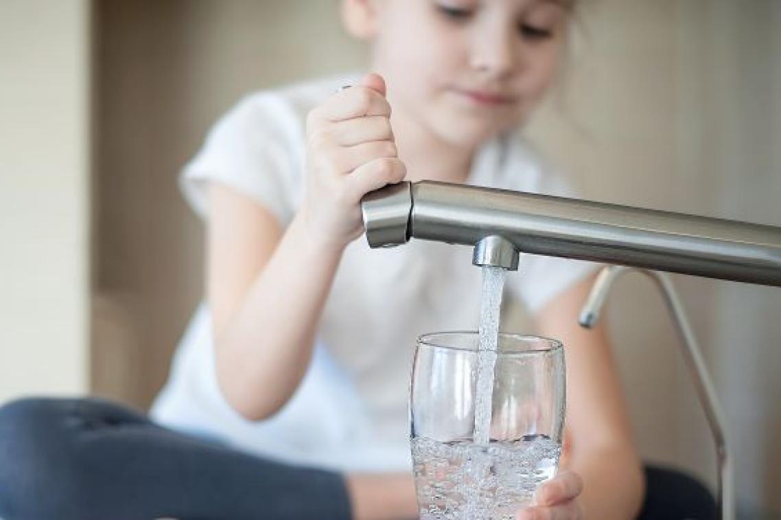 child fills a glass at a water tap