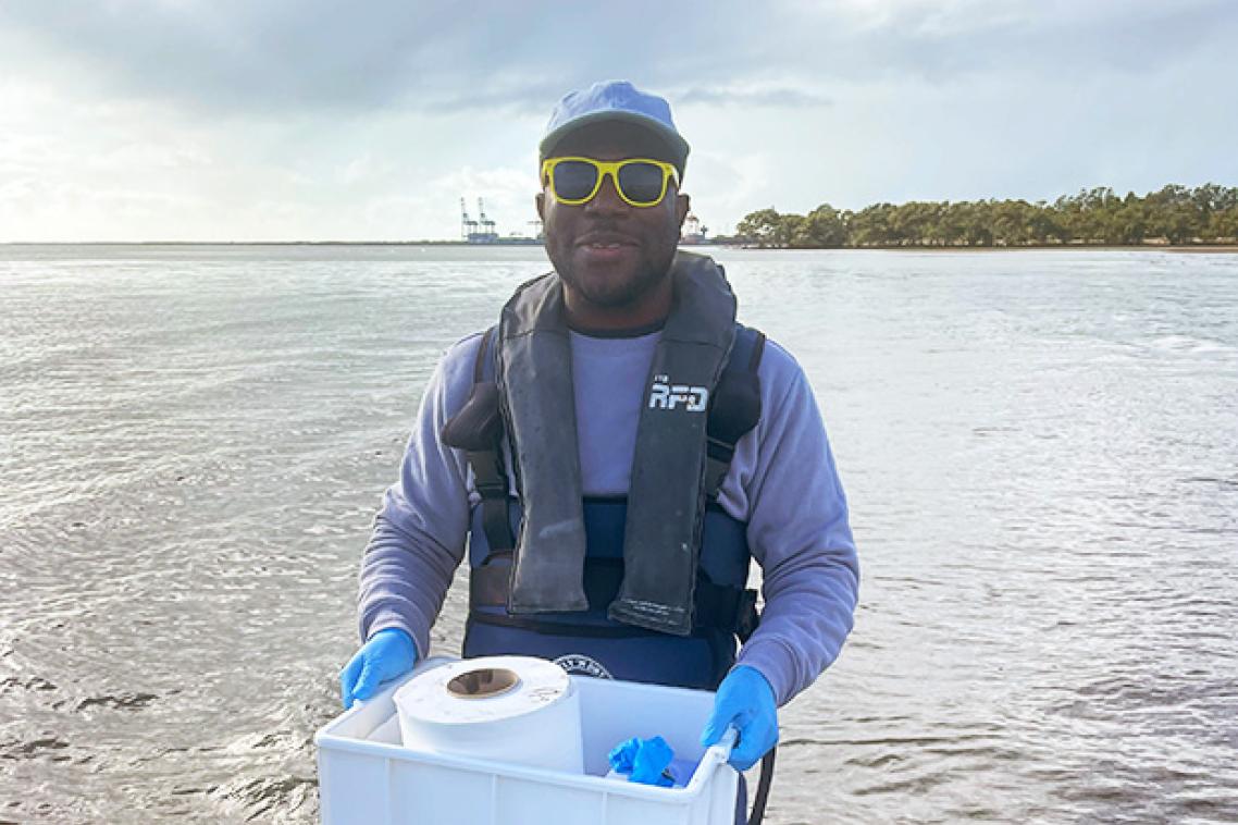 a man stands in water holding a plastic container