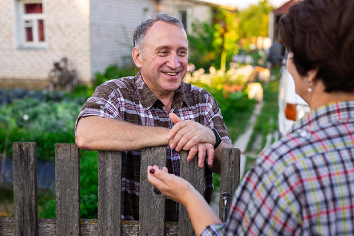 Picture of neighbours talking to each other over the fence.