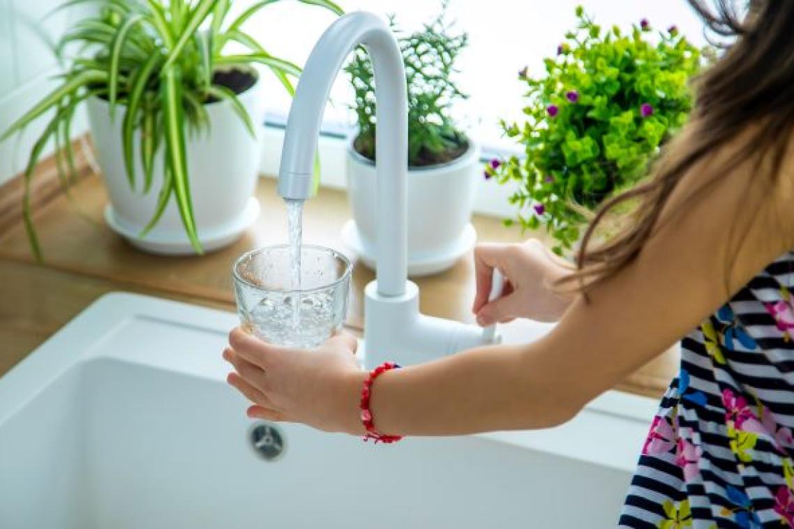 Child filling glass with water from kitchen tap