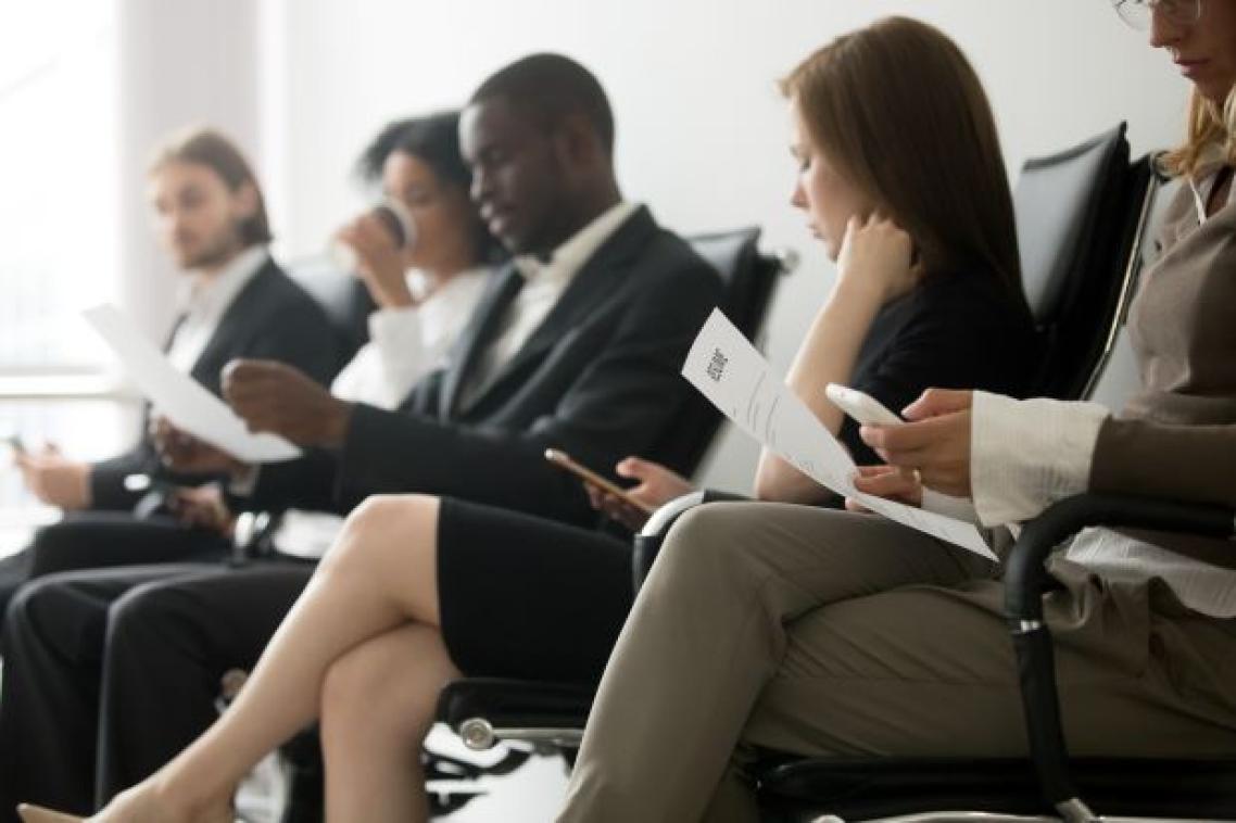 A line of people in suits sitting in chairs holding pieces of paper