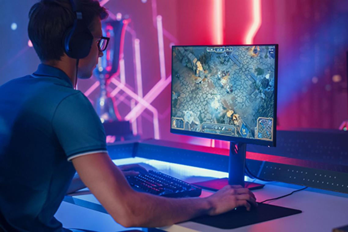 A teenager wearing a headset, while playing a computer game.