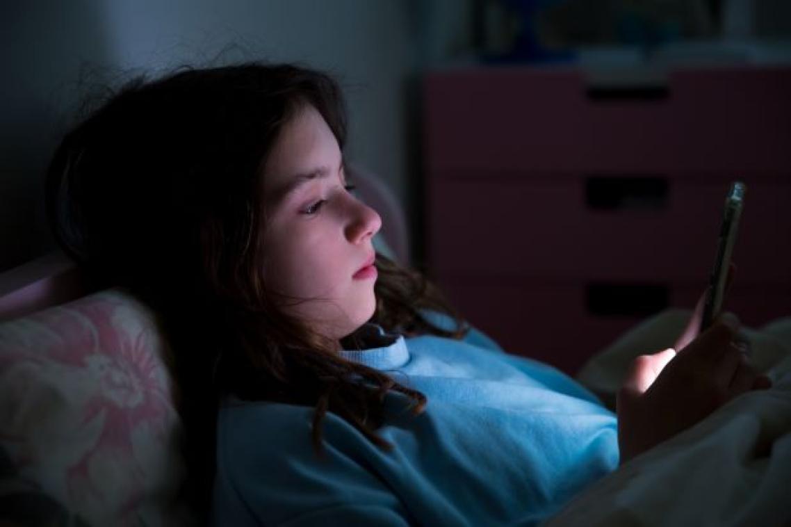 a girl's face is illuminated by the light of a phone screen