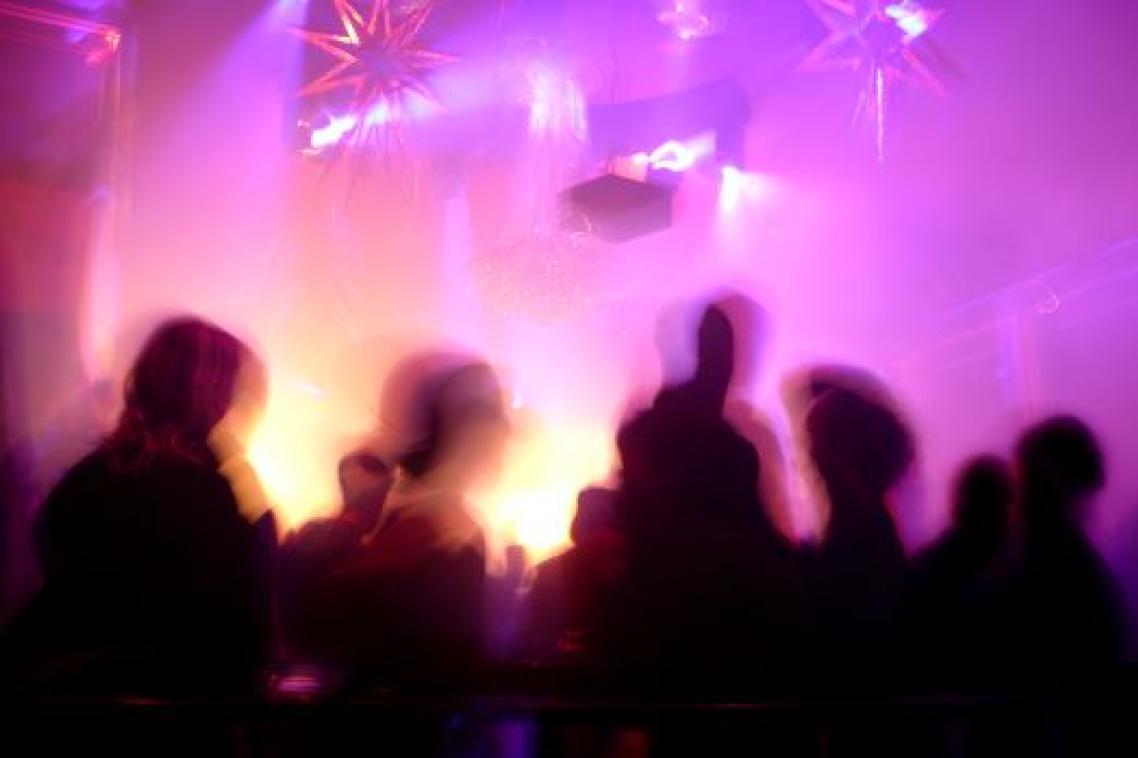 A Silhouette of people in a nightclub surrounded by pink and purple flashing lights