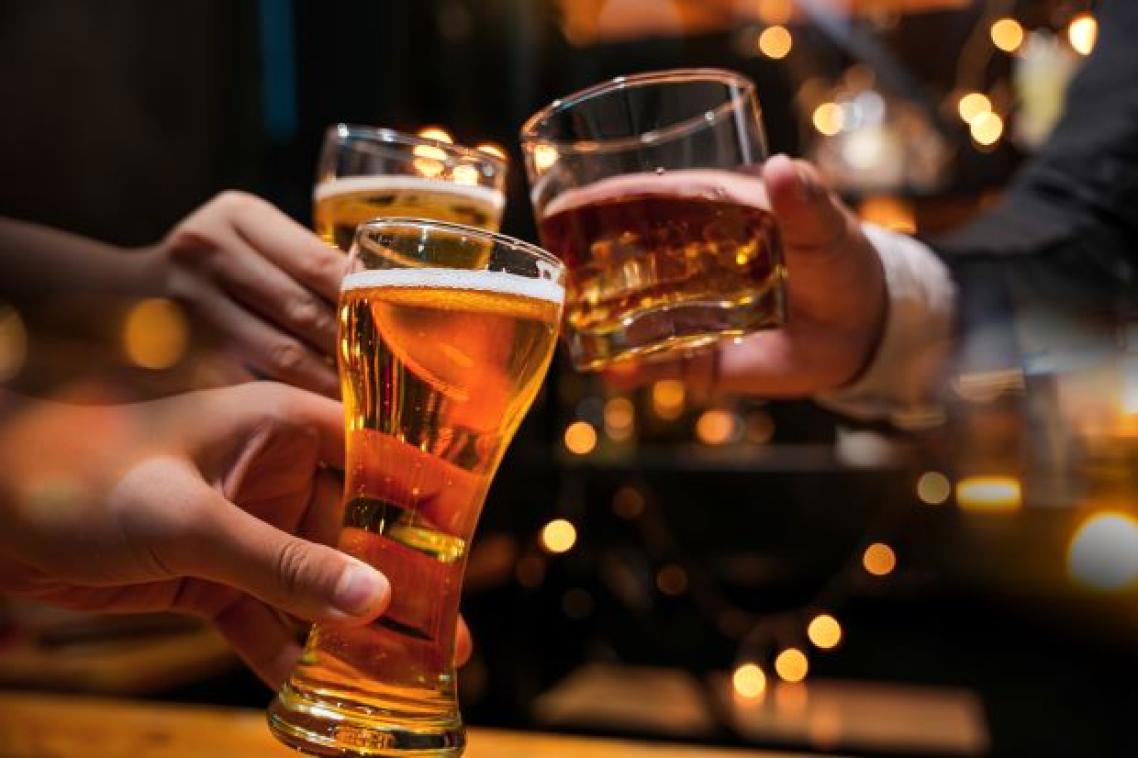 Three hands are holding different alcoholic drinks in a cheers gesture.