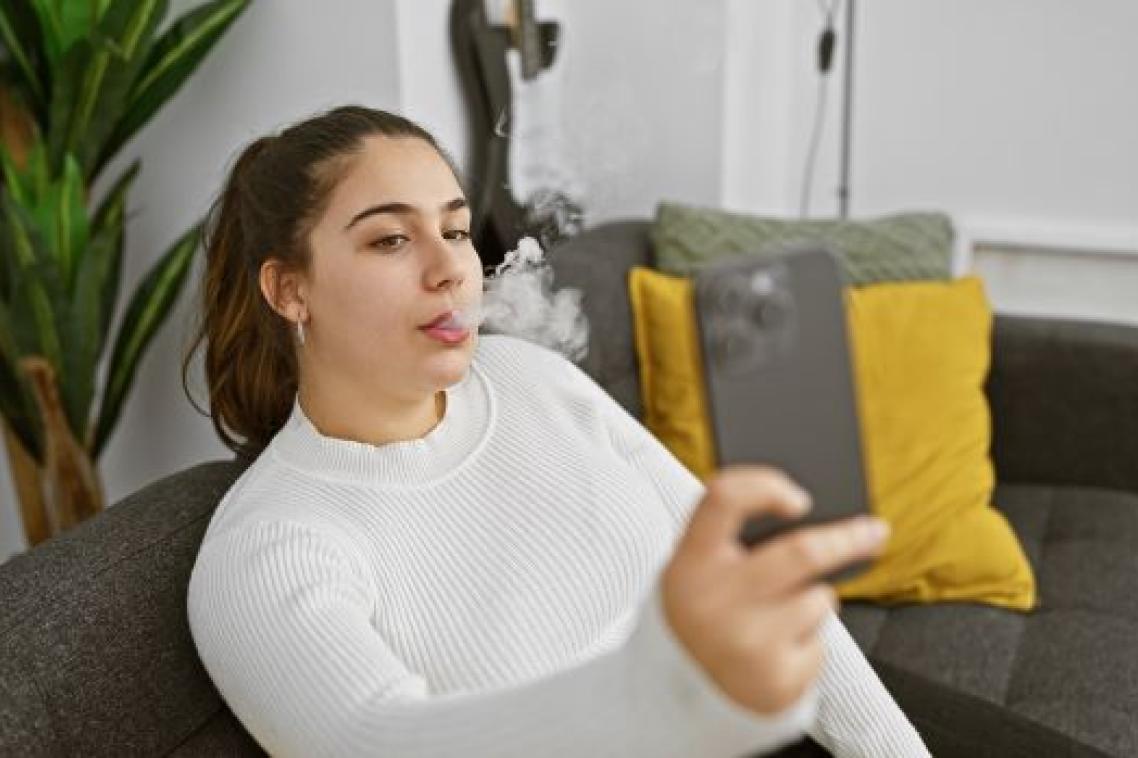 A woman smoking while posing for a phone selfie
