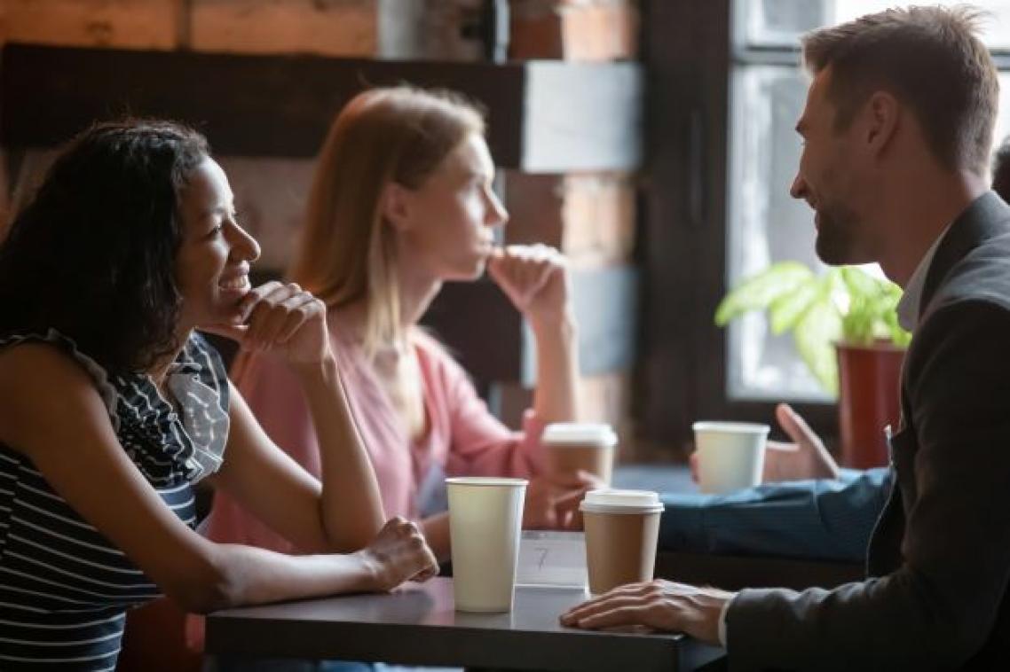 A woman sitting across from a man at a table, the man looks as though he is laughing while the woman is smiling