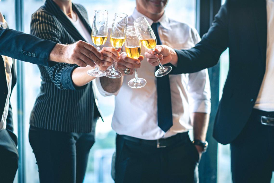 A group of people dressed in corporate wear clinking champagne glasses