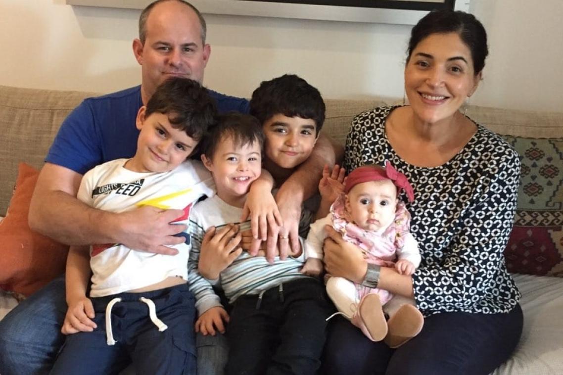 The Holohan family sitting on a couch, with four children on their parents' laps