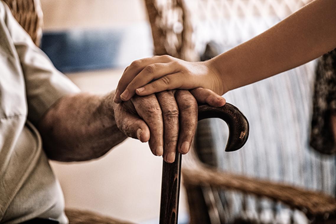 Two hands clasped over a walking stick
