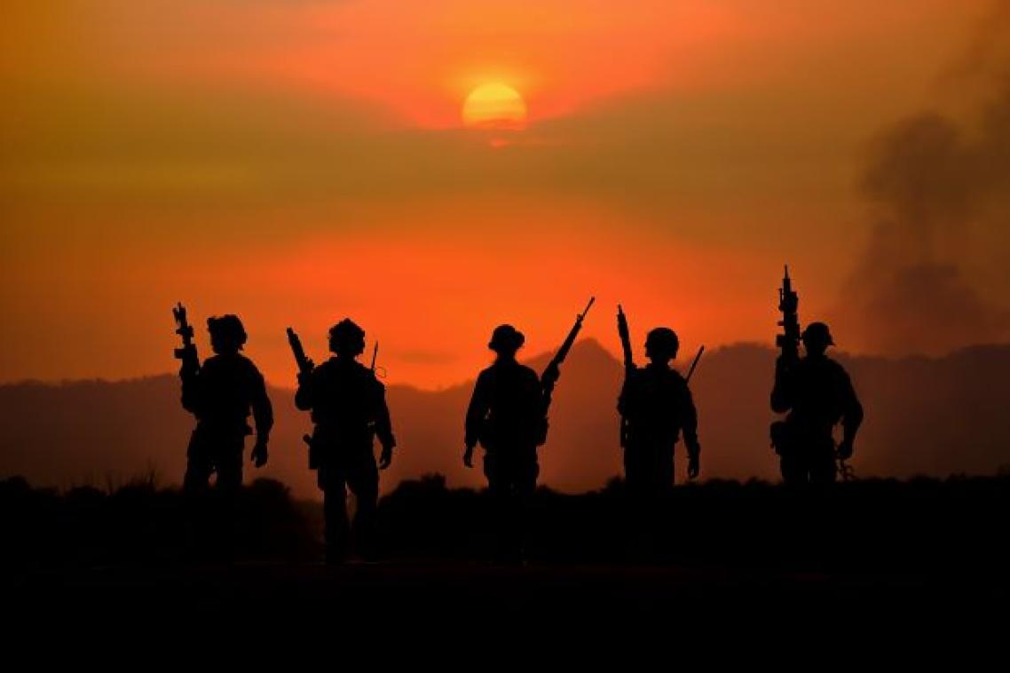 A group of soldiers with weapons silhouetted against a smoky red sky
