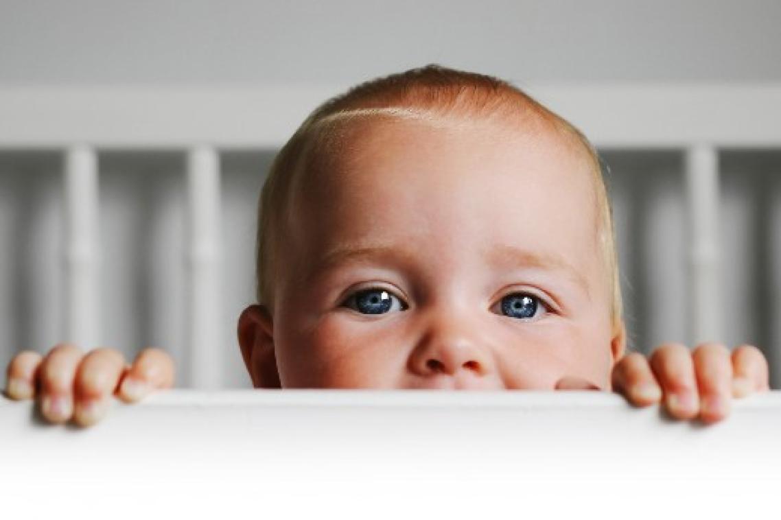 Baby peaking up from crib.