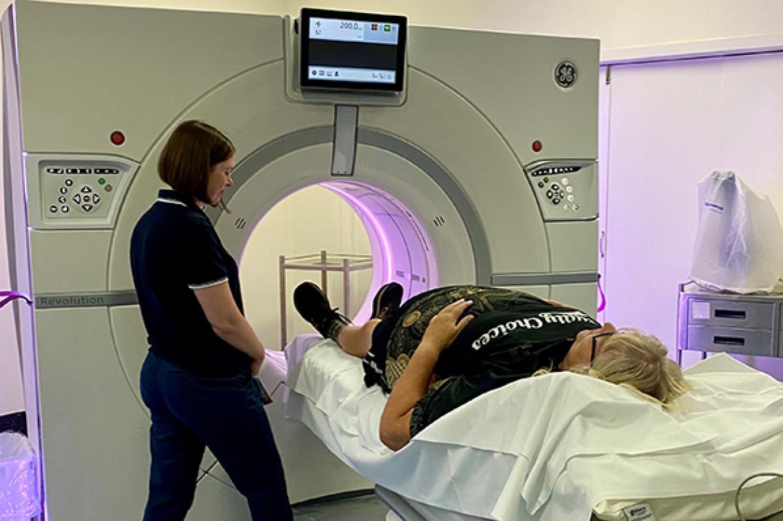 a person lied on a bed with their feet in a round machine and another person stands nearby