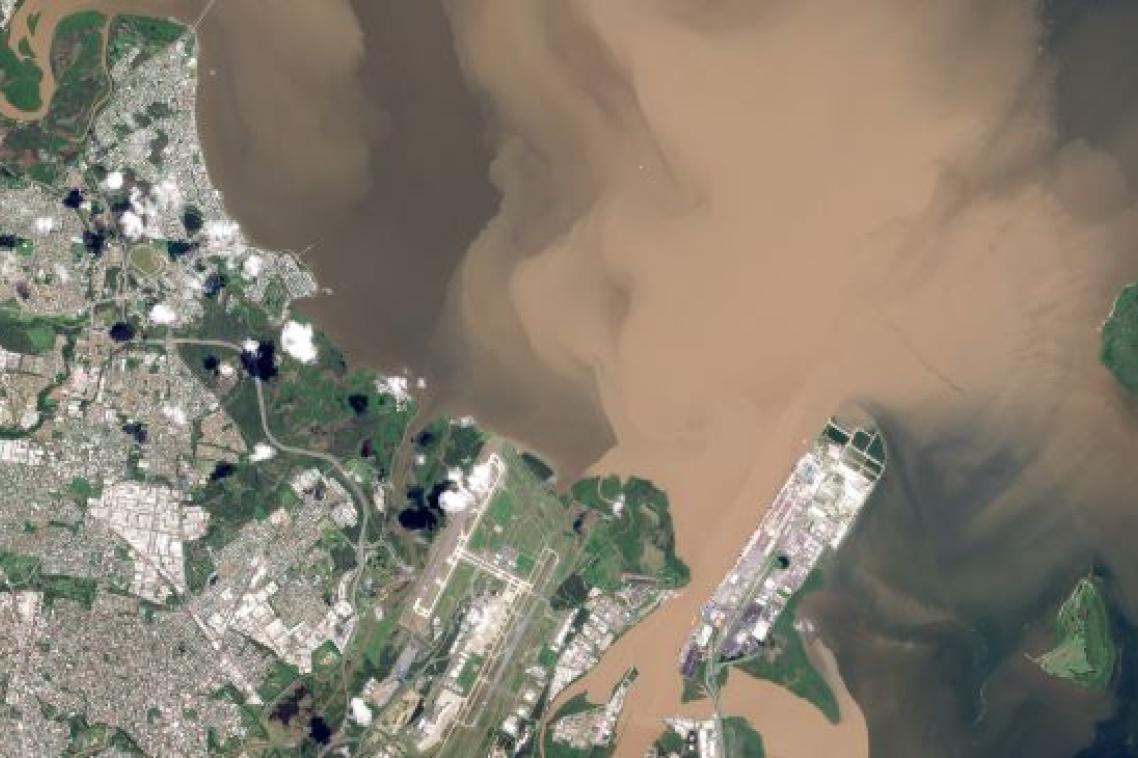 an aerial image of suburbs and a river with brown water coming out of it