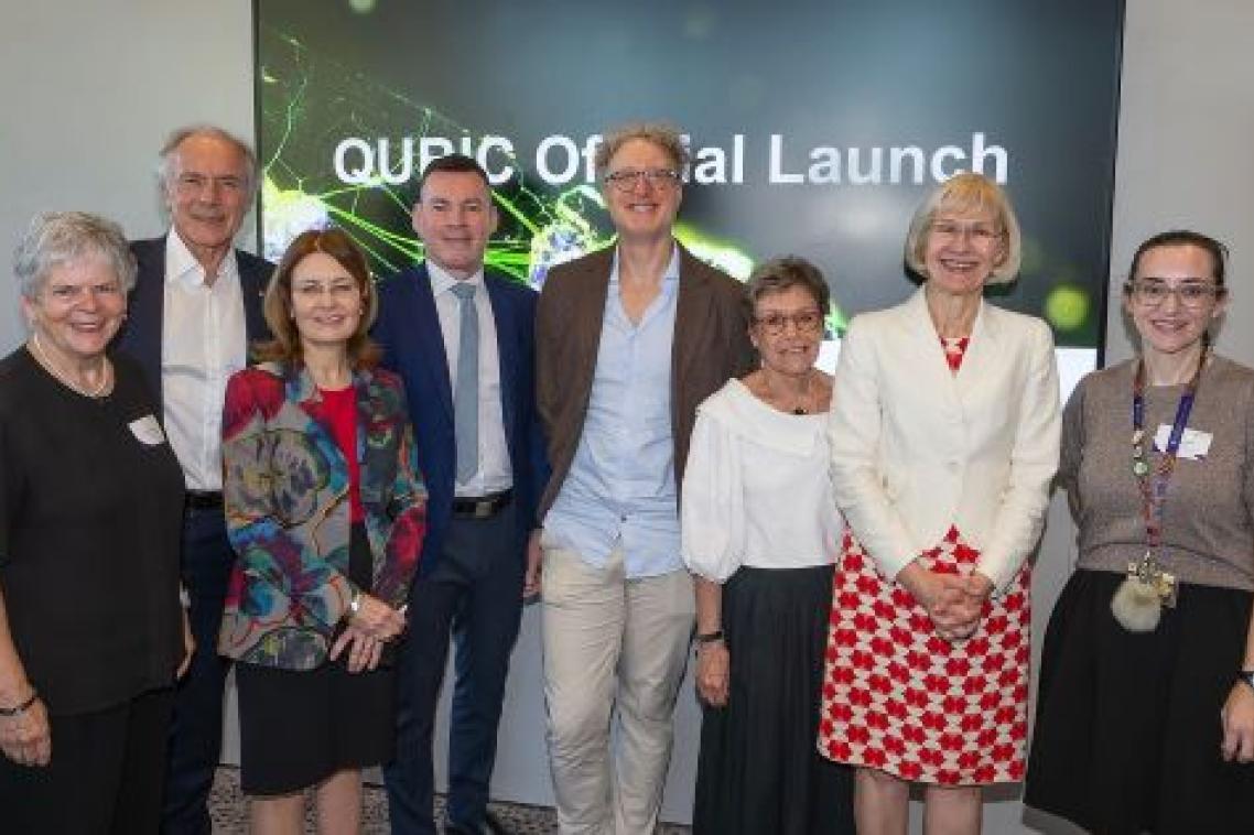 A group of 8 people standing shoulder to shoulder, smiling.
