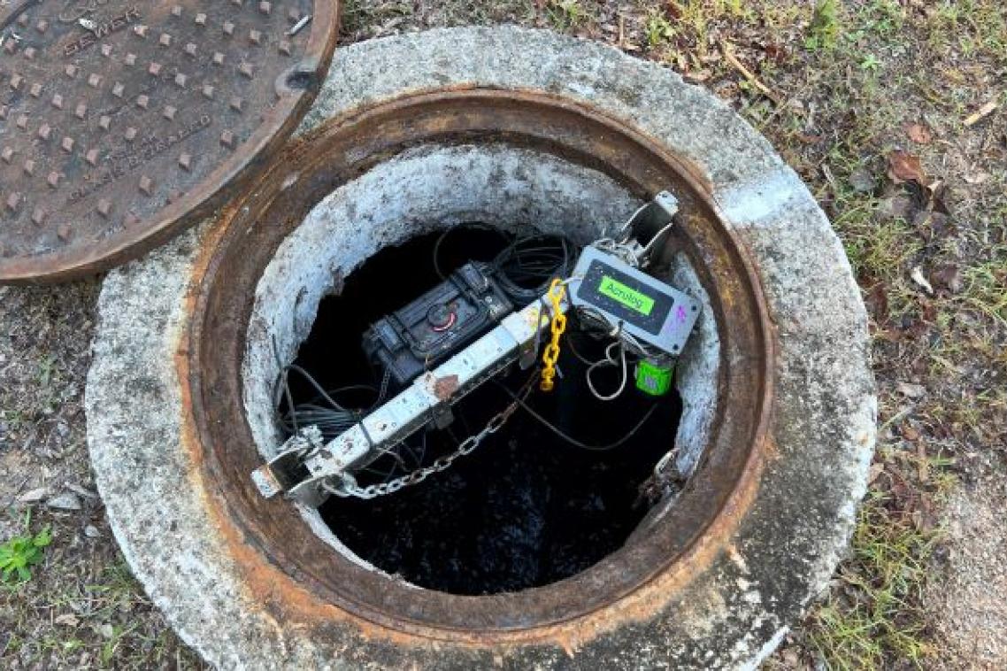 some wires and tech equipment sits inside a concrete-surrounded hole in the ground