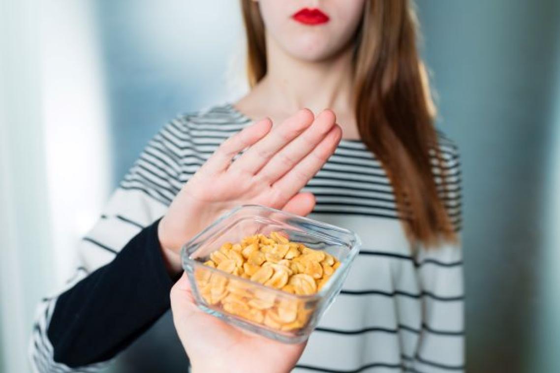 A bowl of peanuts is offered to a young woman who holds up her hand to say no.