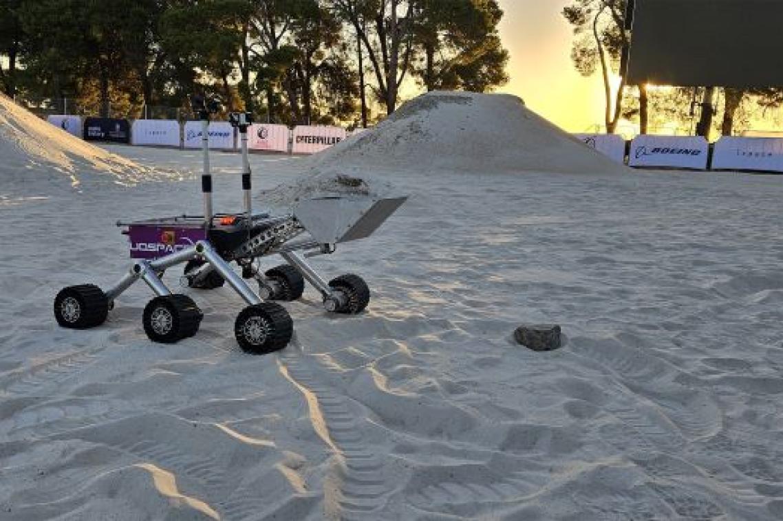 A four wheeled rover with an excavator attachment on a sandy field