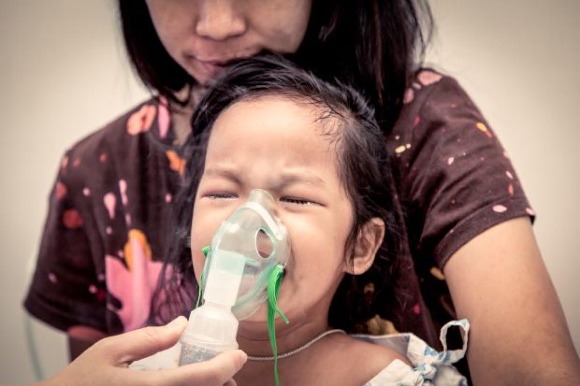 Woman holding inhaler mask to child's face. Image, Adobe.