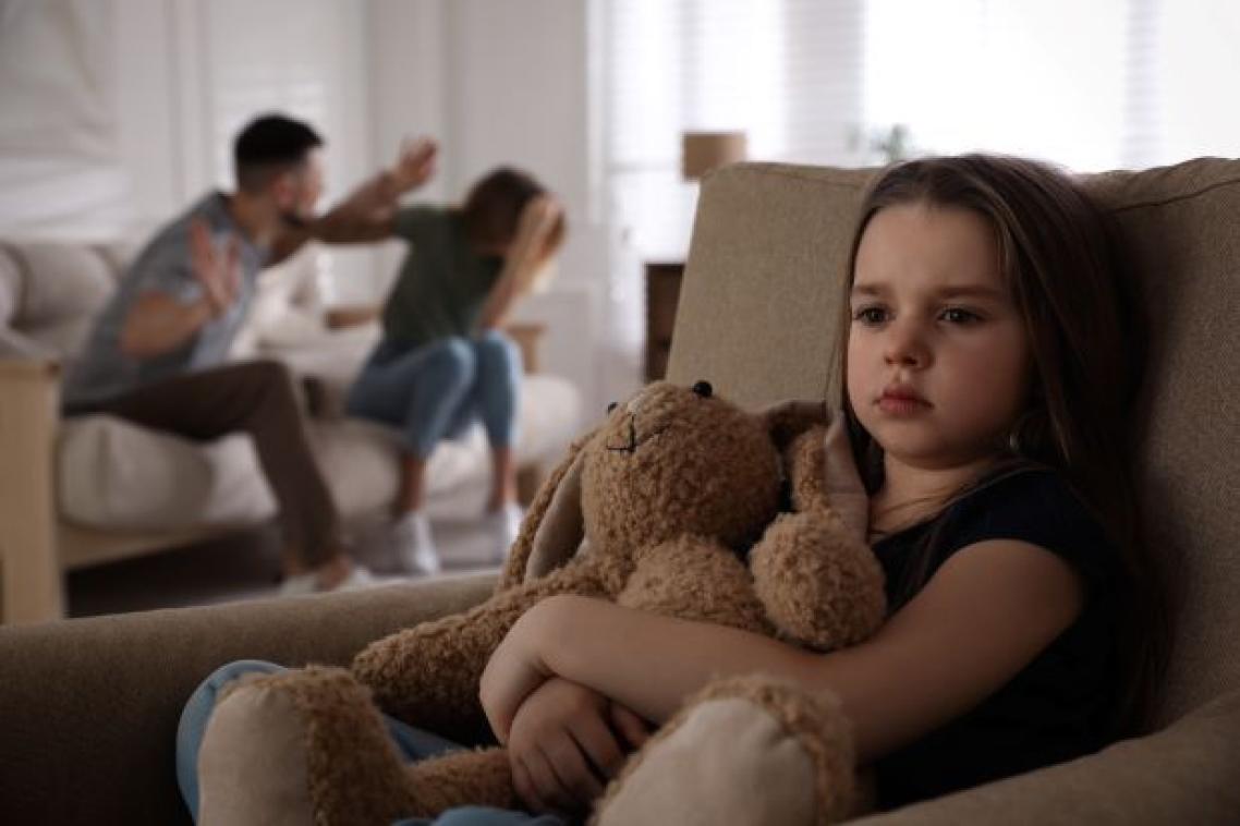 Child holding teddy bear while parents argue in background. Image, Adobe.