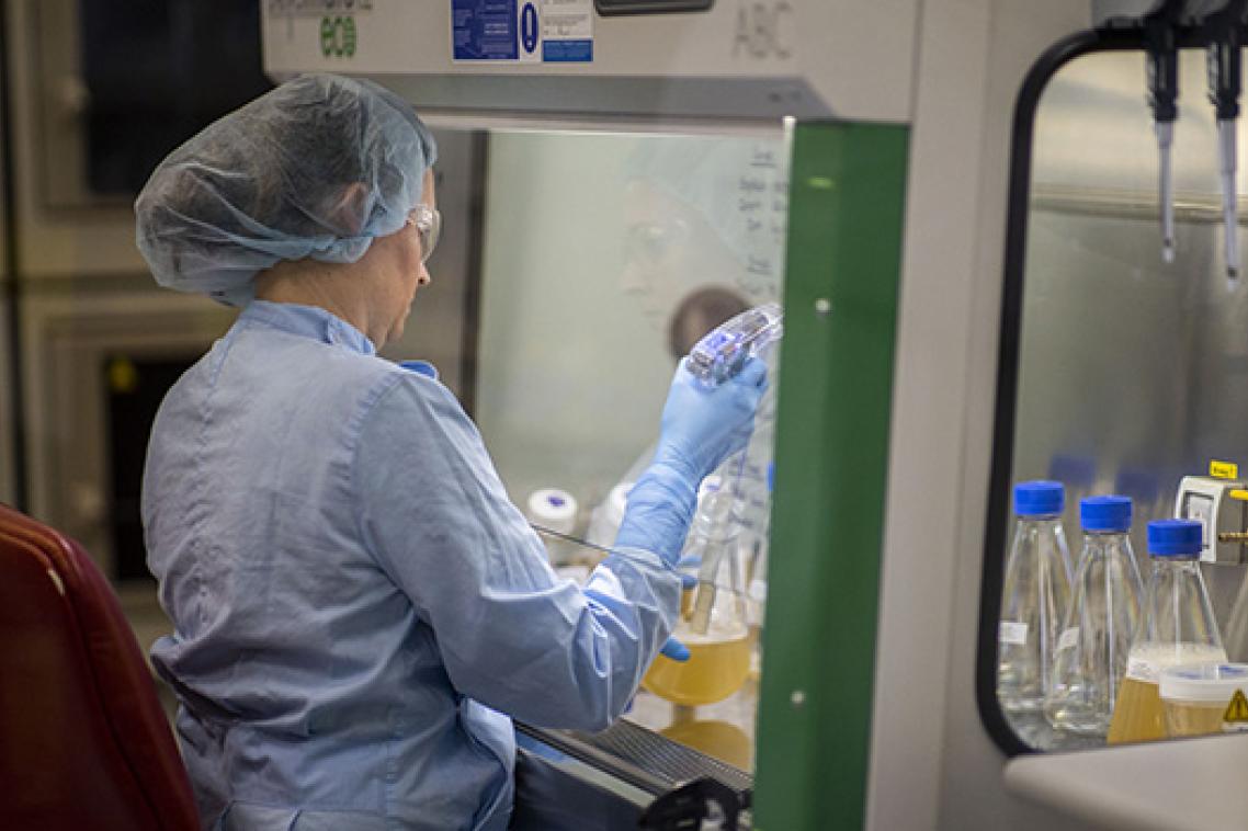 A woman wearing protective clothing using equipment in a science laboratory
